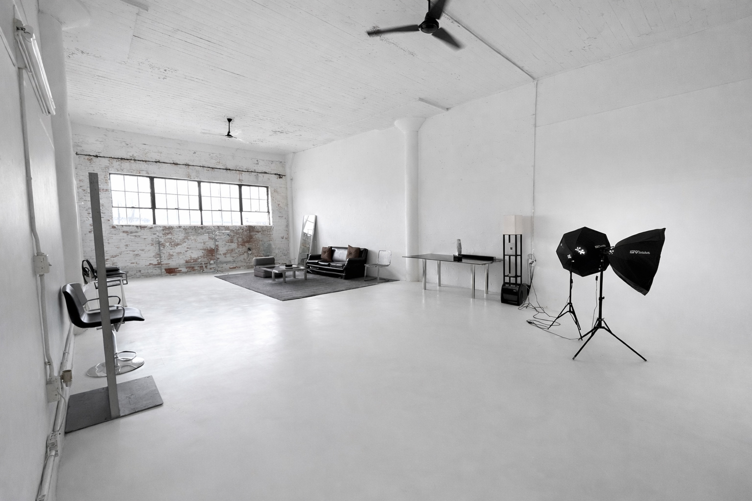 Wide view of Axcer Studio with white cyc wall, lighting setup, and lounge seating